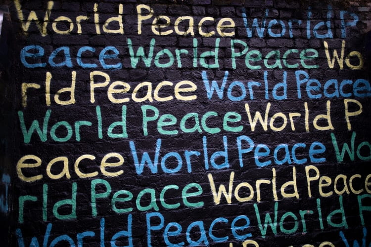 The words "World Peace" repeated in many different colors on a black wall